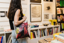 Load image into Gallery viewer, Person with long brown hair facing away from the camera with the Anish Kapoor tote bag hanging on their shoulder.