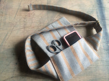 Load image into Gallery viewer, A waist bag in a striped grey and brown material with a phone and a pair of scissors tucked inside it.